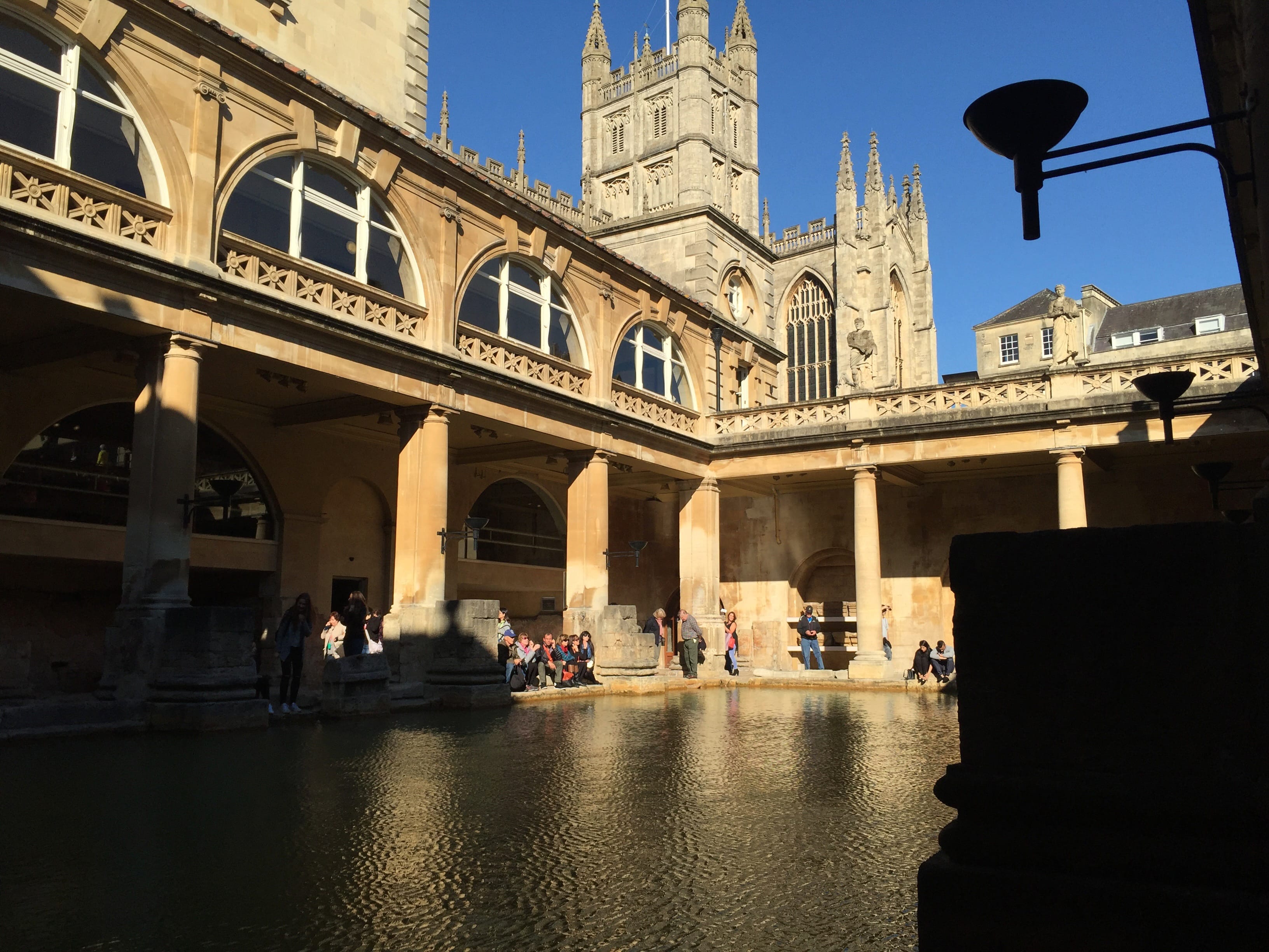 The Roman Baths with the pool in the foreground and The Bath Abbey can be seen in the background through the open top.