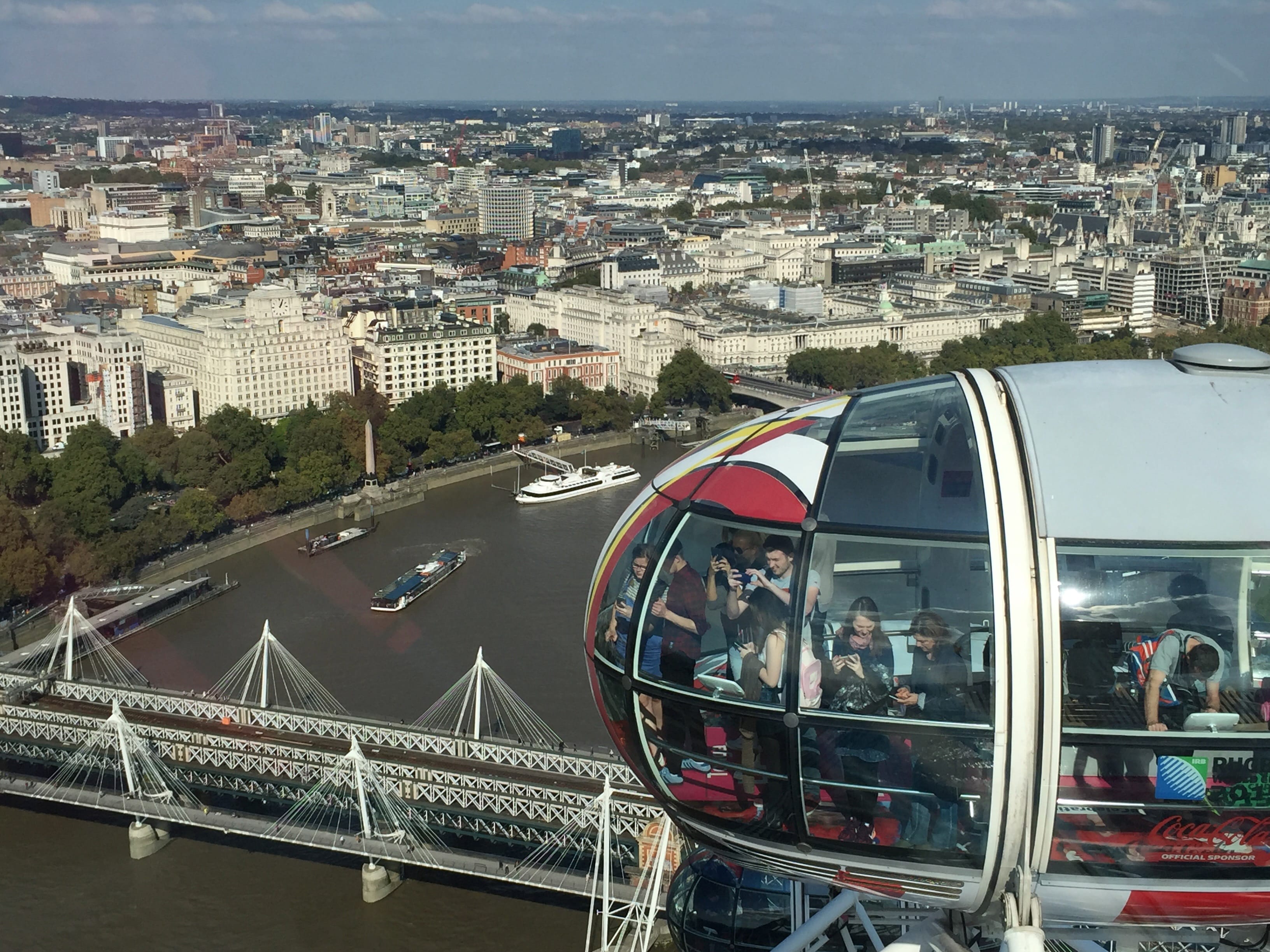 A areal view of London taken from the London Eye with a capsule in the foreground full of tourists taking photos.