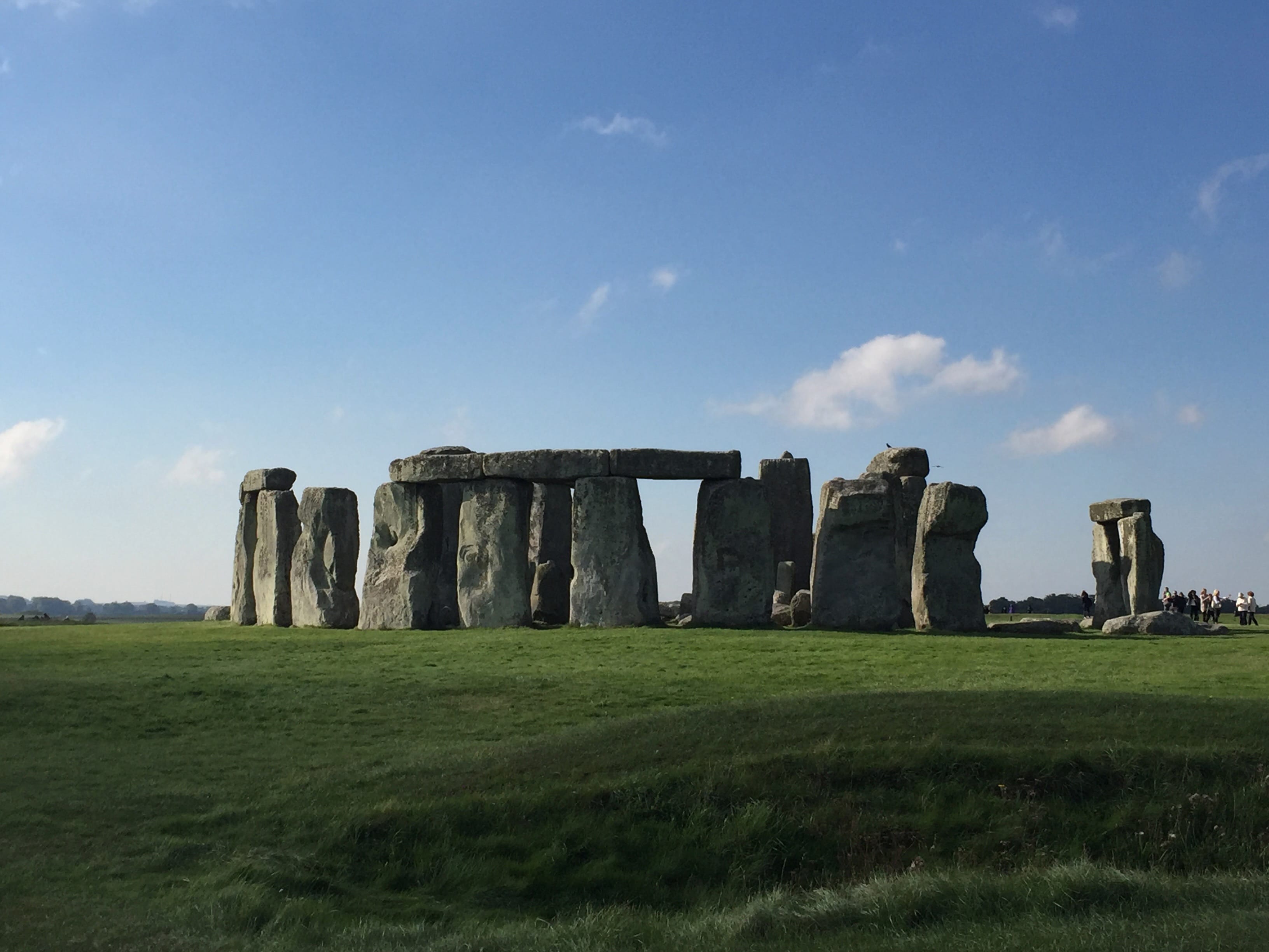 Stonehenge in a green grassy field on a clear day.