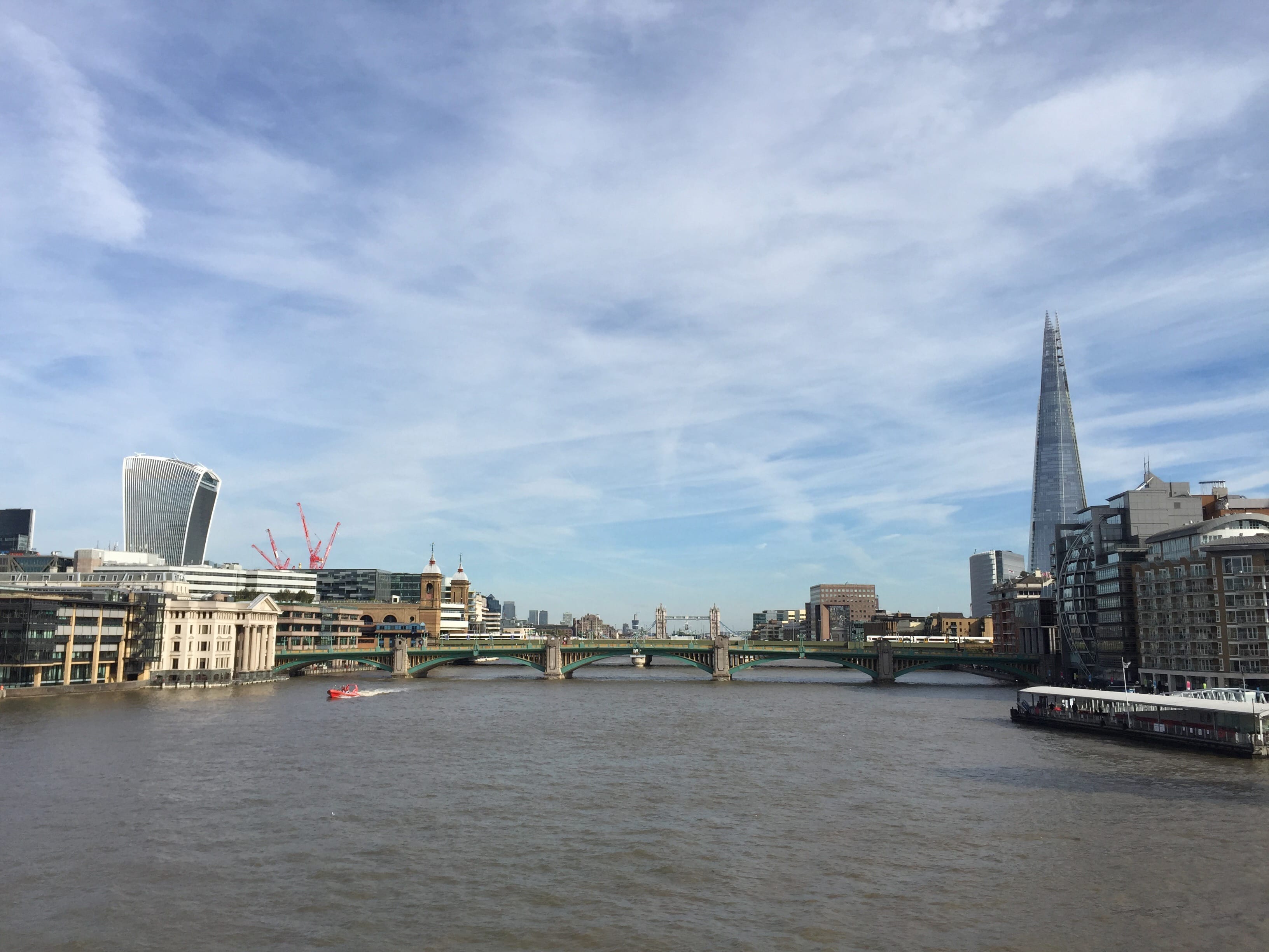 A view down the river thames with multiple bridges in the distance and buildings on each side.