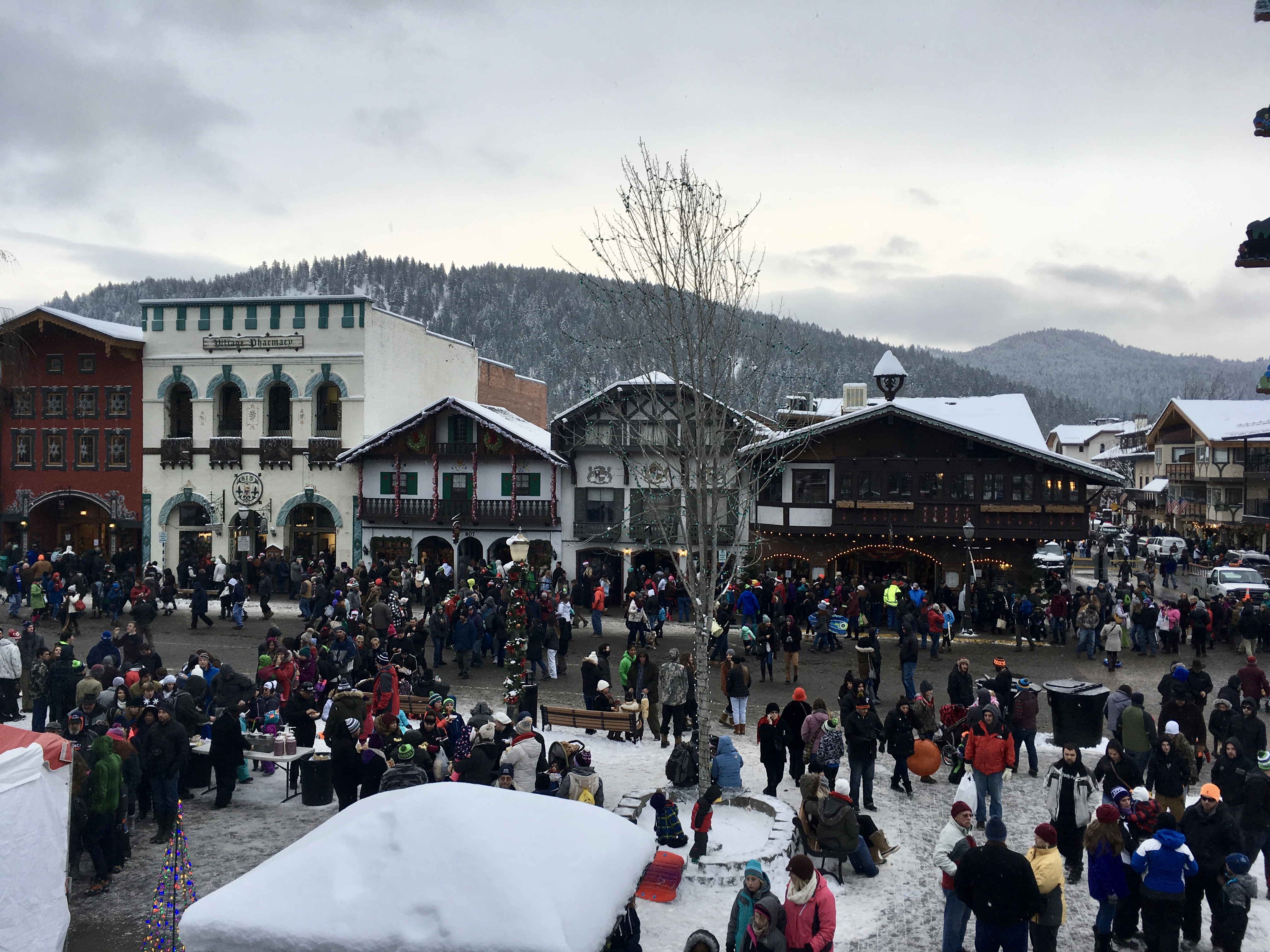 A bavarian village with a lot of people in the streets waiting in line to get in the shops.