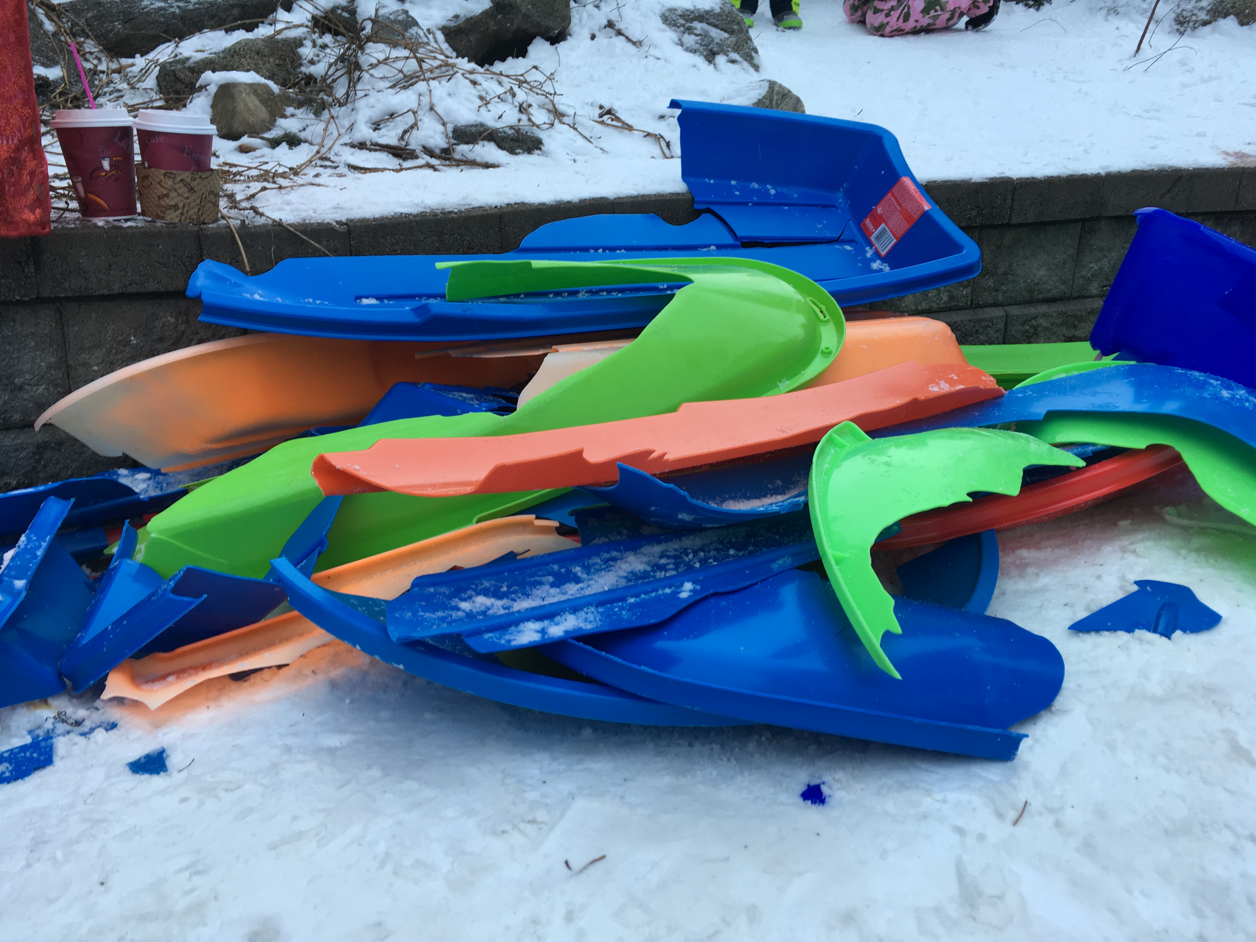 A pile of colorful broken snow sleds.